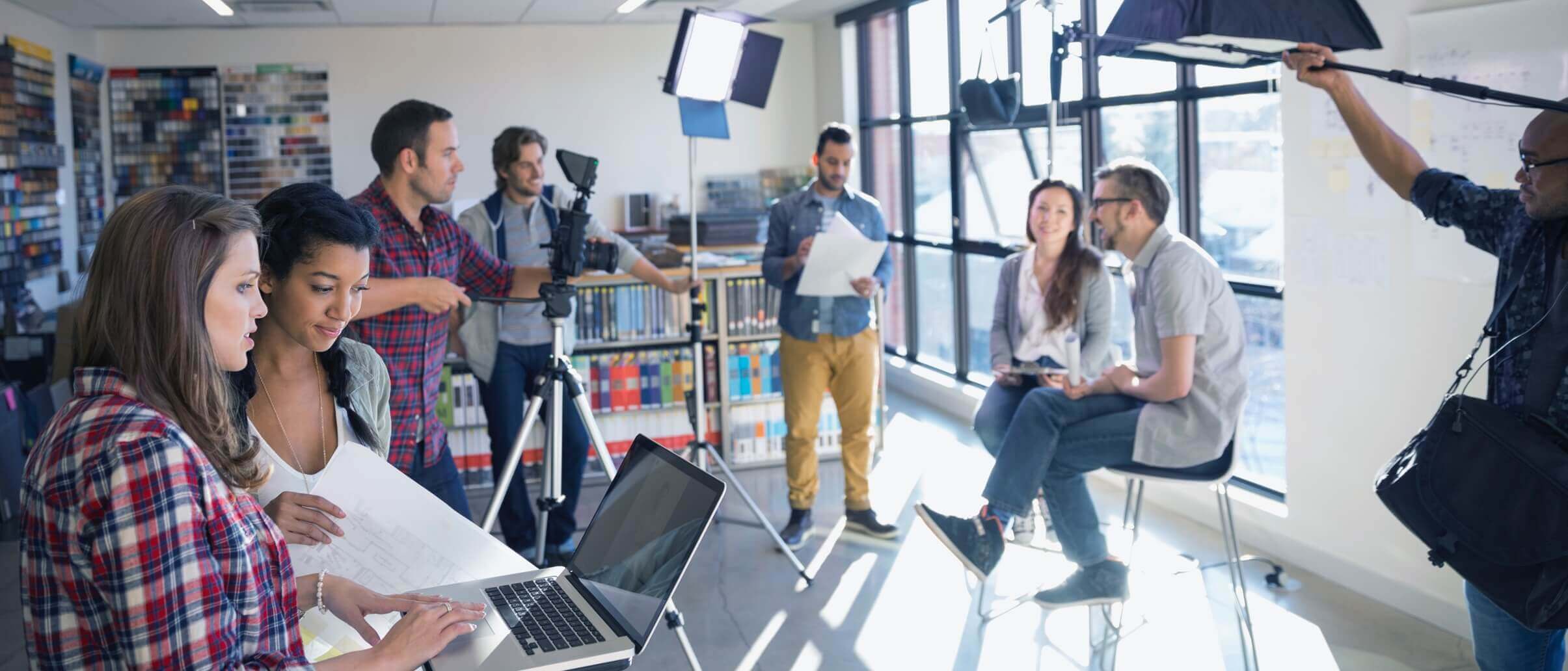 Two young people in chairs being filmed by a crew.